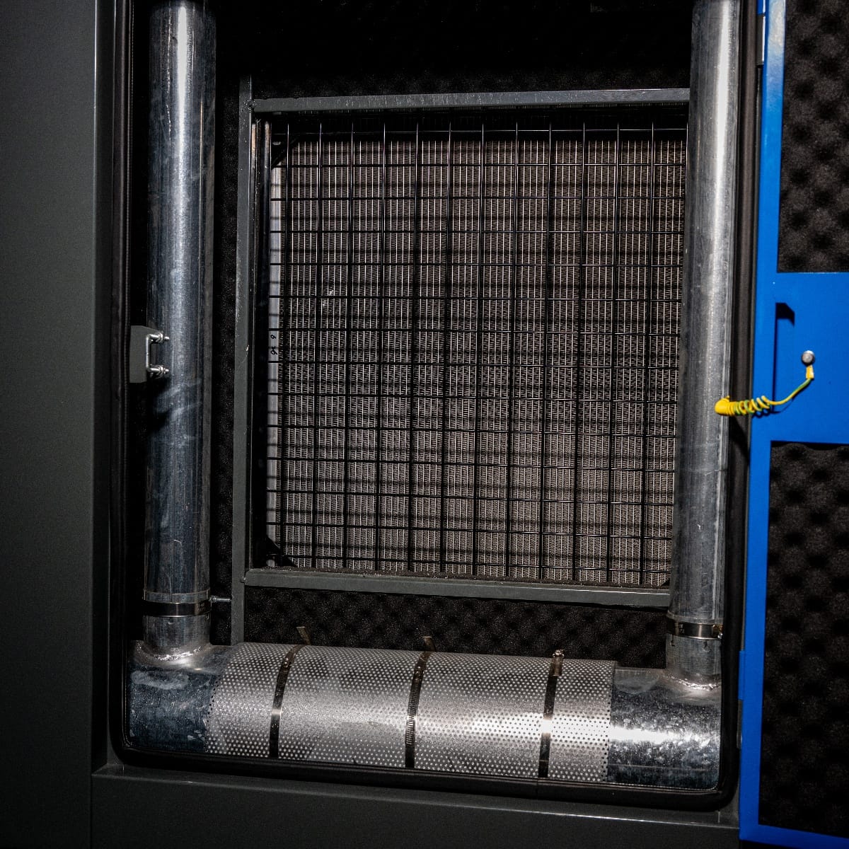 RX-120/150 Stage III Stromgenerator mit Ausschnitt des Innenraums, Sicht auf Rohrleitungssystem und Gitterabdeckung, graue und metallische Oberflächen.