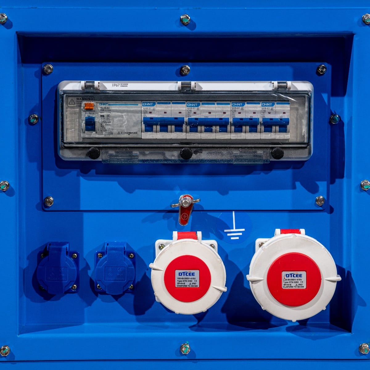 RX-40/50 Stage V Stromgenerator mit blauer Gehäusefront, Sicht auf elektrische Anschlüsse, Sicherungskasten und zwei rot-weißen Steckdosen.